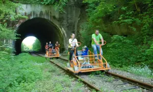 Rodzina na drezynach w Bieszczadach, przejeżdża obok tunelu kolejowego.