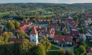 Widok z lotu ptaka na Lipnicę Murowaną. Widać kościół z wieżą, domy z czerwonymi dachami i otaczające lasy. To piękne miejsce oferuje wiele atrakcji.