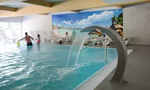 Rodzina bawi się w basenie z wodospadem w hotelu Pokrzywna. Relaks w gorzelnianym klimacie.