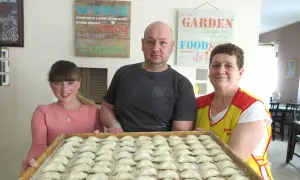 Rodzina przygotowuje pierogi. Na tacy czeka pełna micha menu, gotowa do gotowania.