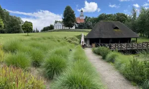 Malowniczy krajobraz z wieżą kościelną i chatą z krytym strzechą dachem. Wspaniałe mogilno atrakcje przyrodnicze i architektoniczne.