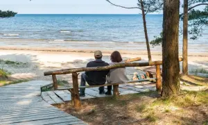 Para relaksu nad morzem, para siedzi na ławce, patrząc na fale. Idealne miejsce na wypoczynek w sanatoriach nad morzem.
