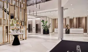 Eleganckie lobby hotelu Radisson Collection Hotel Warsaw z nowoczesnymi windami, recepcją i dekoracjami roślinnymi.
