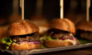 Mini burgery z sałatą, cebulą i ogórkiem na tacy. Idealne do pastelowa menu.