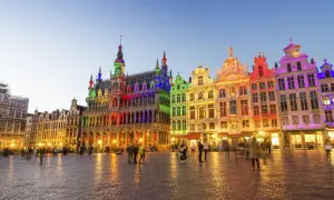 Kolorowe budynki na Grand Place w Brukseli, idealne na święta w Belgii. Ludzie spacerują po brukowanym placu o zmierzchu.