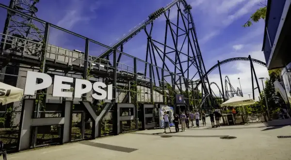 Kolejki w Energylandii, gdzie czeka adrenalina na rollercoasterze Pepsi. Ludzie wchodzą na teren parku, by doświadczyć emocji.