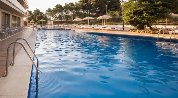 Basen w Lloret de Mar we wrześniu. Idealna pogoda na relaks przy basenie, z leżakami i parasolami.
