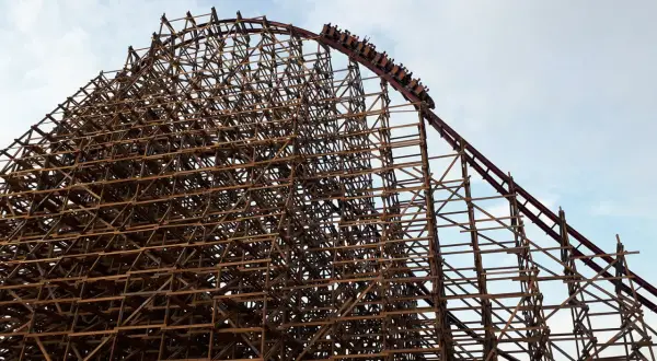 Drewniana konstrukcja rollercoastera w Energylandii, z wagonikami wjeżdżającymi na szczyt. Czy Energylandia jest otwarta w deszcz?