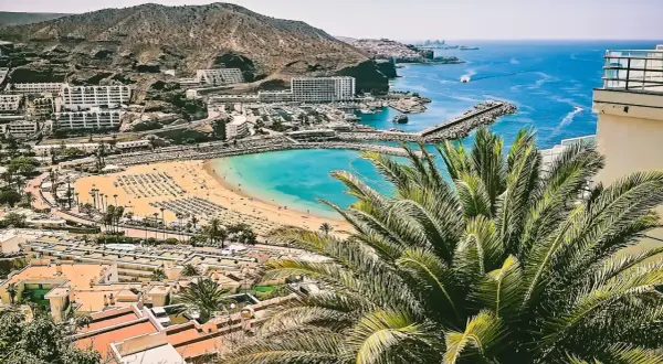Gran Canaria w czerwcu: słoneczna plaża, turkusowe morze i palmy. Idealna pogoda na wakacje.