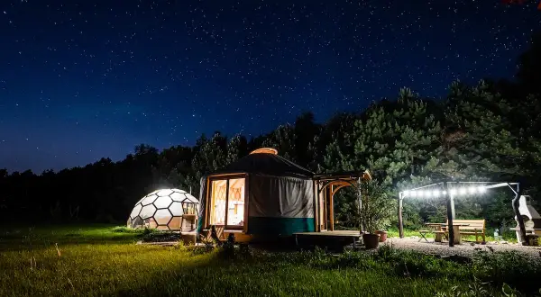 Nocne niebo nad Podkarpaciem. Jurt i kopuła w trawie, oświetlone gwiazdami i lampkami. Idealne romantyczne miejsca na wypoczynek.