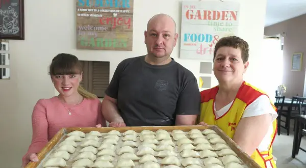 Rodzina przygotowuje pierogi. Na tacy czeka pełna micha menu, gotowa do gotowania.