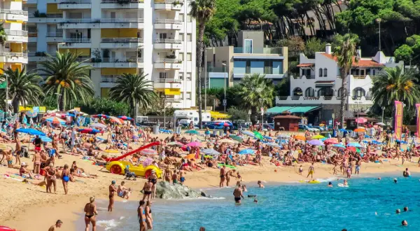 Lloret de Mar pogoda kwiecień: plaża pełna ludzi, słońce, palmy i turkusowe morze. Idealny dzień na wypoczynek.