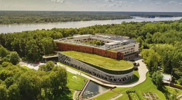 Nowoczesny hotel nad Narwią z zielonym dachem i stawem, otoczony lasem. Idealne miejsce na wypoczynek.