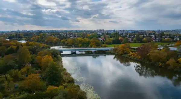 Jesioro Czerniakowskie jesienią, z mostem i miastem w tle.