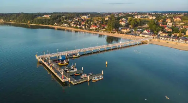 Molo w Mechelinkach z łodziami i plażą. To idealne miejsce na spacer i podziwianie widoków, jedna z głównych atrakcji Mechelinki.