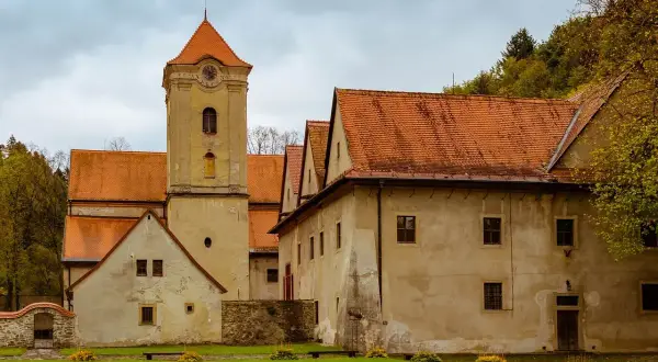 Czerwony Klasztor z wieżą zegarową i pomarańczowymi dachami. Sprawdź cennik zwiedzania tego zabytku.