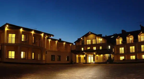 Hotel Rusałka w Okunince nocą, oświetlony, z widokiem na fasadę i balkony.