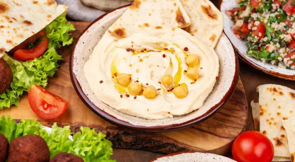 Pyszne dania kuchni libańskiej: kremowe hummus, falafel, sałatka tabbouleh i świeże pity. Idealne na wspólny posiłek.