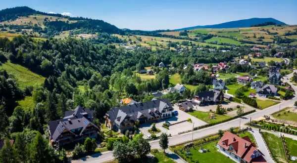 Gorce: malownicza wieś z pensjonatami i domami w górskim krajobrazie. Idealne miejsce, by sprawdzić, gorce gdzie najlepiej nocować.