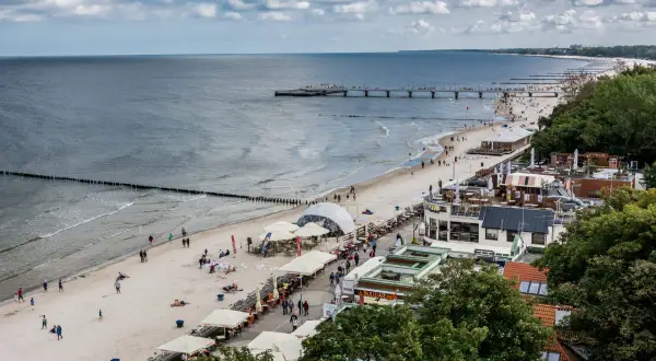 Plaża nad Bałtykiem, molo, restauracje i spacerowicze. Idealne miejsce na tanie wczasy we wrześniu w Polsce.
