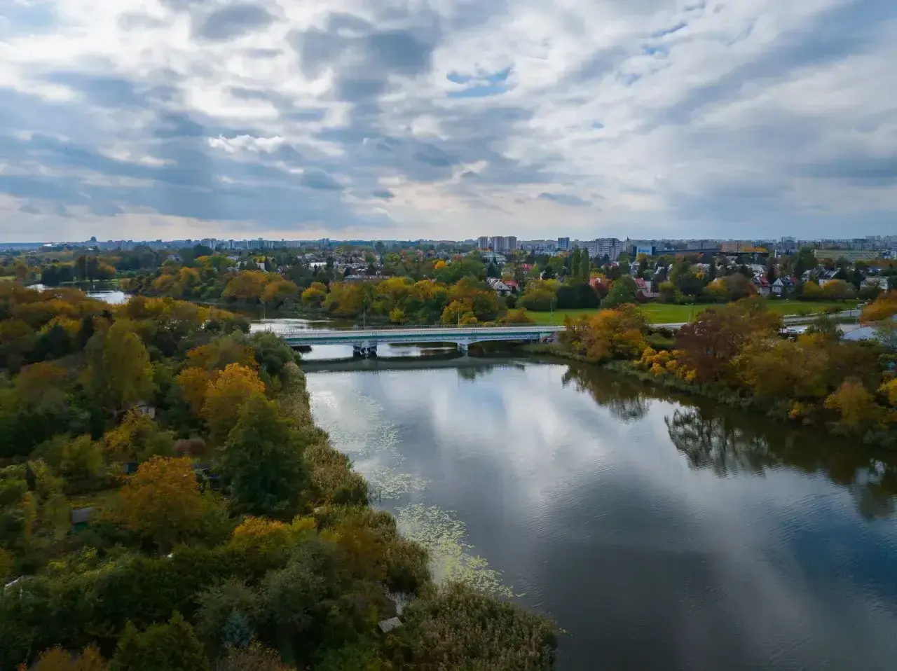Jesioro Czerniakowskie jesienią, z mostem i miastem w tle.