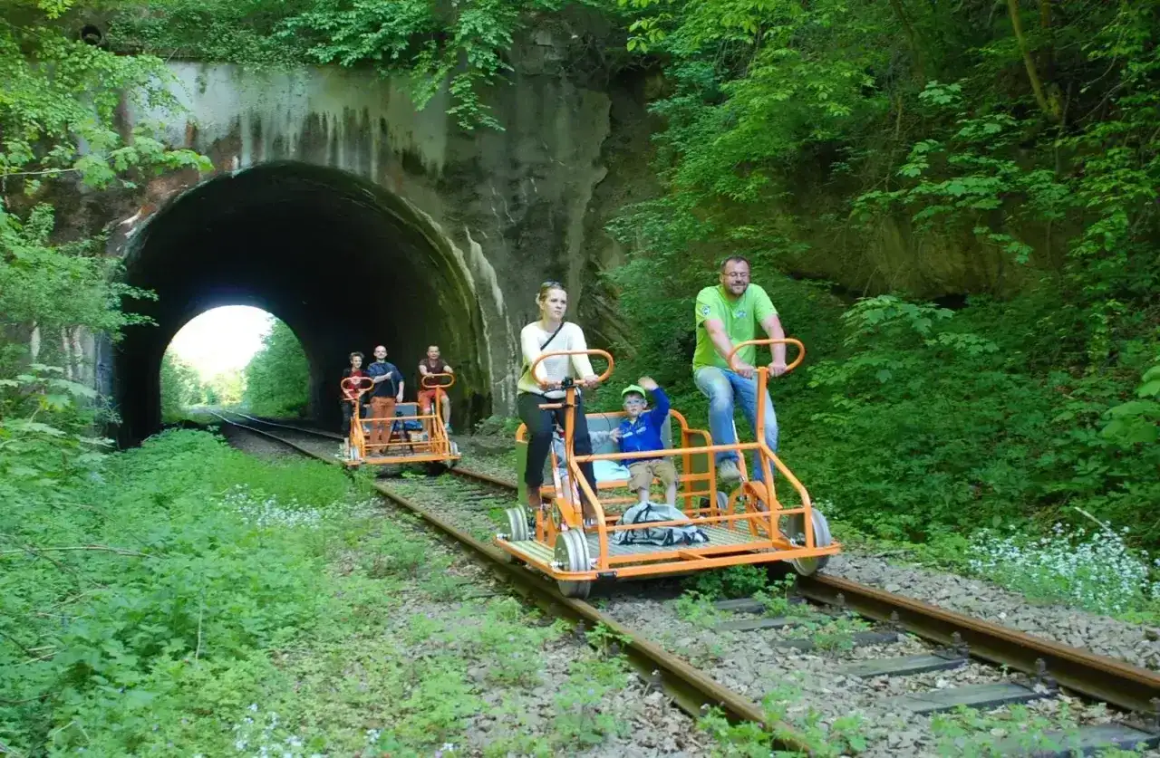 Rodzina na drezynach w Bieszczadach, przejeżdża obok tunelu kolejowego.