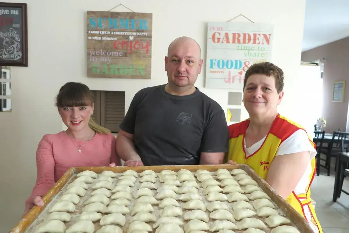 Rodzina przygotowuje pierogi. Na tacy czeka pełna micha menu, gotowa do gotowania.