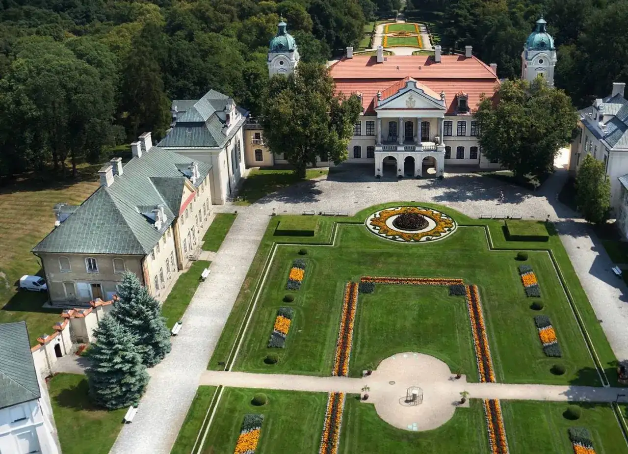Pałac i ogrody w Kraśniku to wspaniałe atrakcje. Widok z lotu ptaka ukazuje barwne rabaty kwiatowe, zadbane trawniki i architekturę pałacową.
