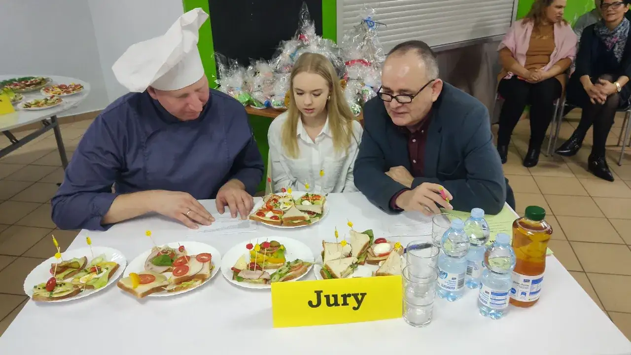 Jury ocenia kanapki na konkursie kulinarnym. Szef kuchni Remigiusz Rączka z restauracji wita uczestników.