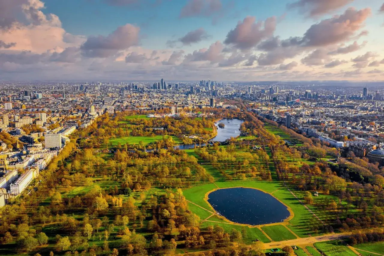 Jesienna panorama Hyde Park w Londynie, z jeziorem Serpentine i otaczającym miastem w tle.