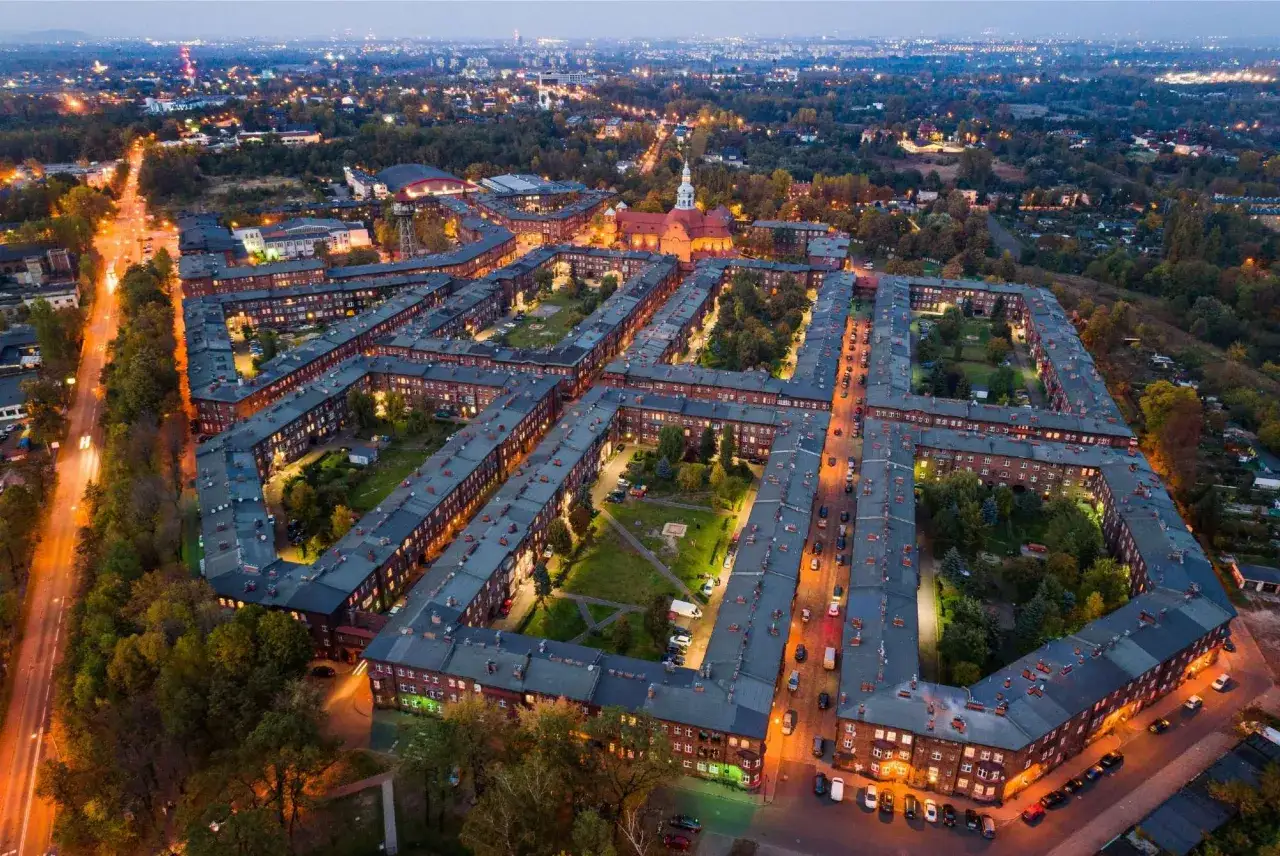 Osiedle Giszowiec w Katowicach nocą, z charakterystyczną zabudową tworzącą podwórka. To nietypowe atrakcje Katowice, które warto odkryć.