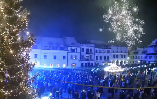 Świąteczna iluminacja i fajerwerki nad rynkiem w Kazimierzu Dolnym. Tłumy ludzi świętują nadchodzące wydarzenia.