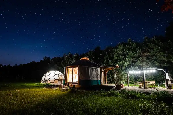 Nocne niebo nad Podkarpaciem. Jurt i kopuła w trawie, oświetlone gwiazdami i lampkami. Idealne romantyczne miejsca na wypoczynek.